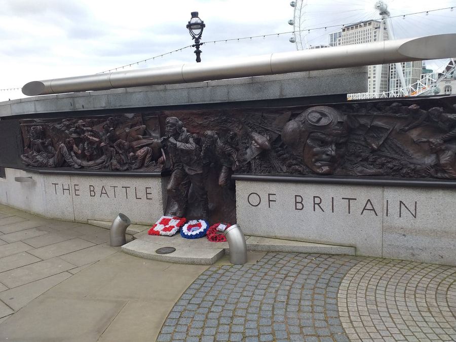 The Battle of Britain Monument on Victoria Embankment, London, with bronze relief sculptures and wreaths laid at its base